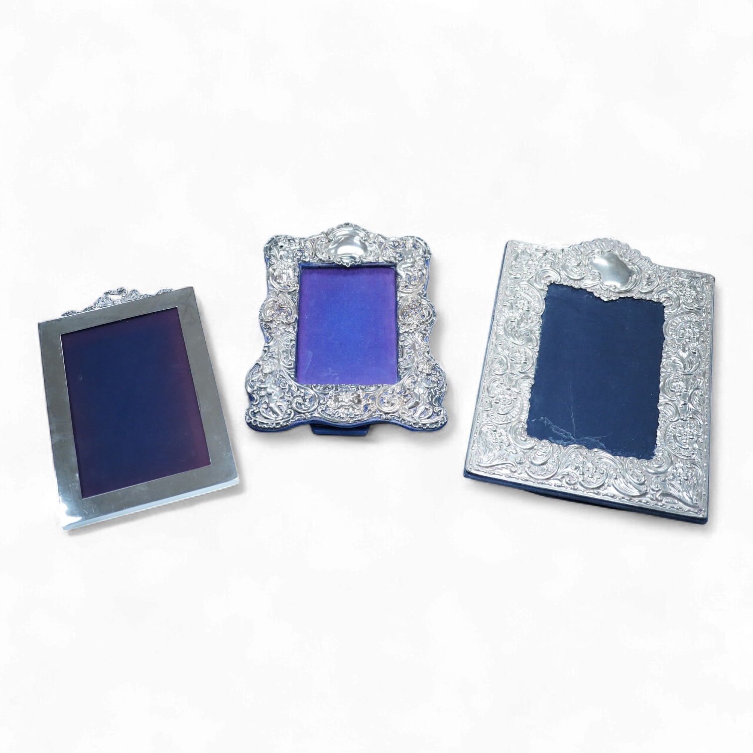 An Edwardian repousse silver mounted photograph frame, by Synyer & Beddoes, Birmingham, 1901, 23.4cm, together with a George V plain silver rectangular photograph frame, with ribbon bow crest, Stuart Clifford & Co, Londo